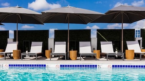 A swimming pool area with lounge chairs and umbrellas.