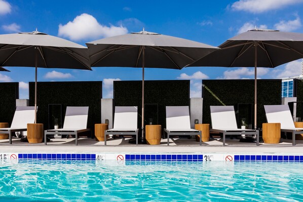 Un espace piscine avec des chaises longues et des parasols.