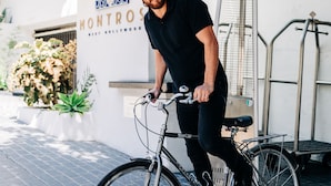 A man on a bicycle in front of a building with a sign that reads "Montrose."