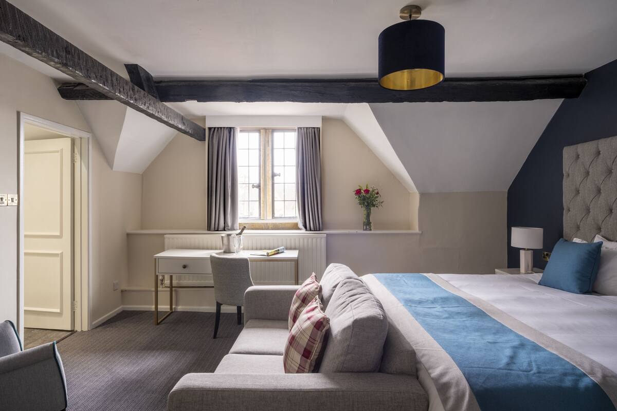 Une chambre à coucher avec un lit, un bureau, une chaise et une fenêtre avec des rideaux.
