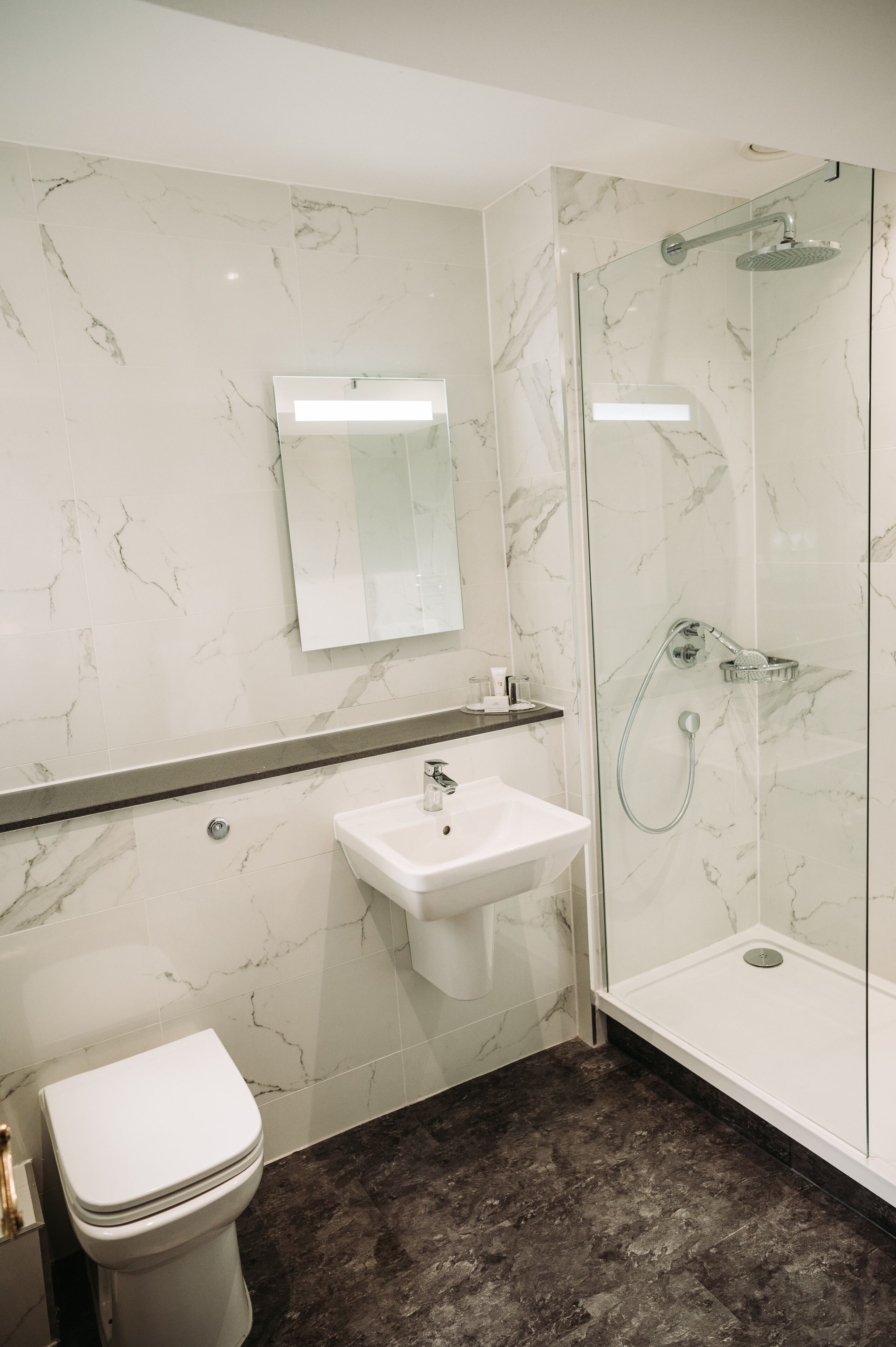 Een badkamer met toilet, wastafel en douchecabine.