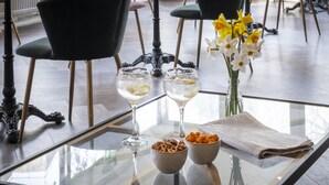 A dining area with tables and chairs, a glass partition, and a view of greenery outside. - Whately Hall (Banbury)