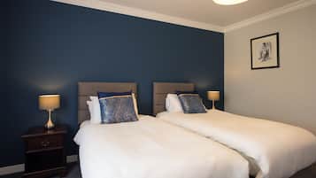 Habitación de hotel con dos camas, una mesita de noche y una lámpara de pared.