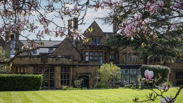 Un bâtiment historique doté d’une pelouse bien entretenue et agrémenté de magnolias en fleurs.