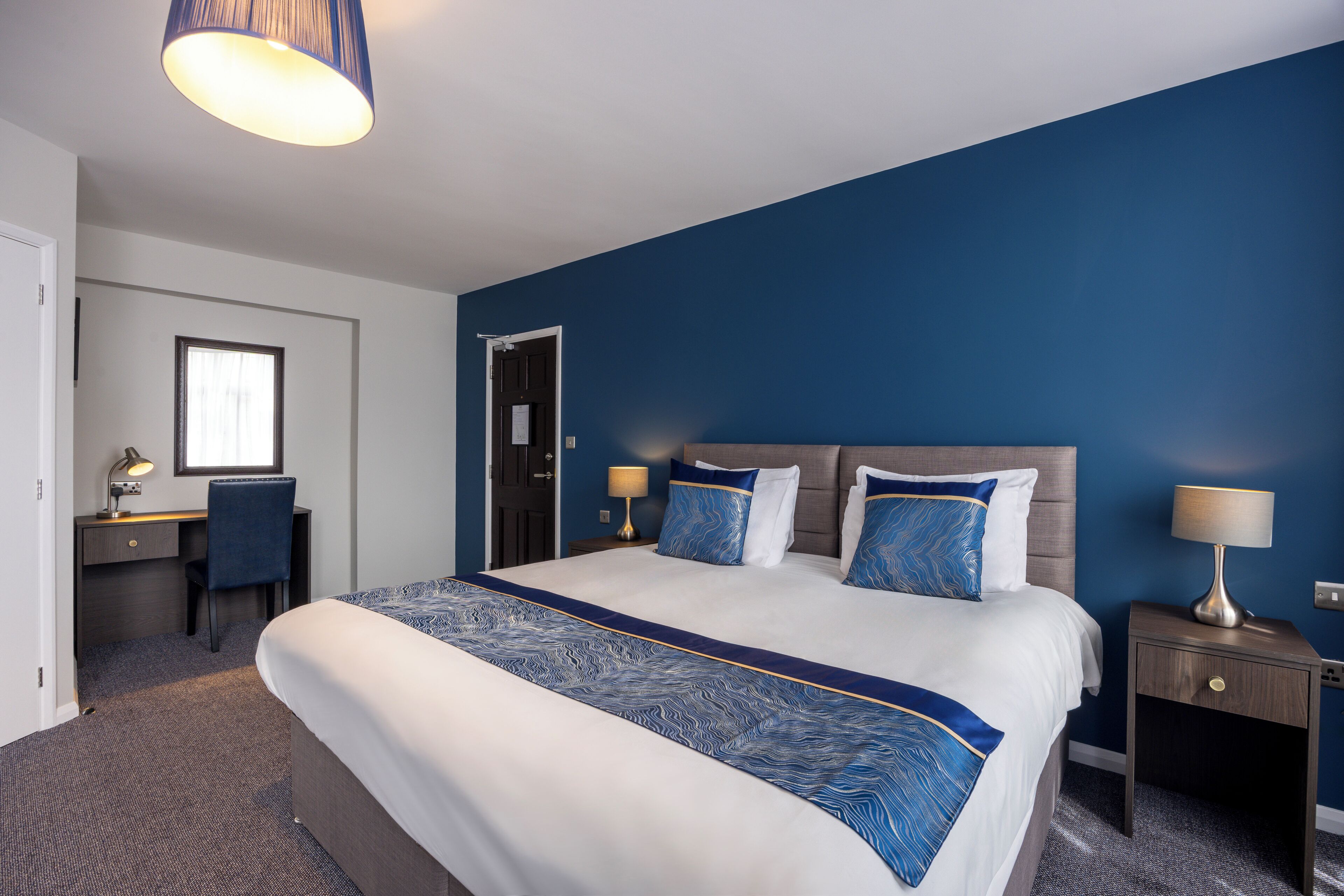 Een hotelkamer met een groot bed, een bureau en een stoel.