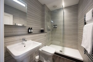 Un baño moderno con ducha de vidrio, lavamanos blanco y un inodoro.