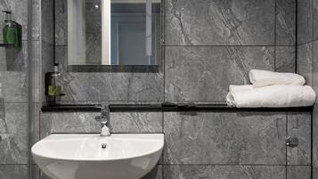 A modern bathroom with a white sink, a mirror above it, and a white toilet.