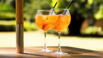 Dos vasos de jugo de naranja sobre una mesa de madera, con un objeto metálico a un lado.