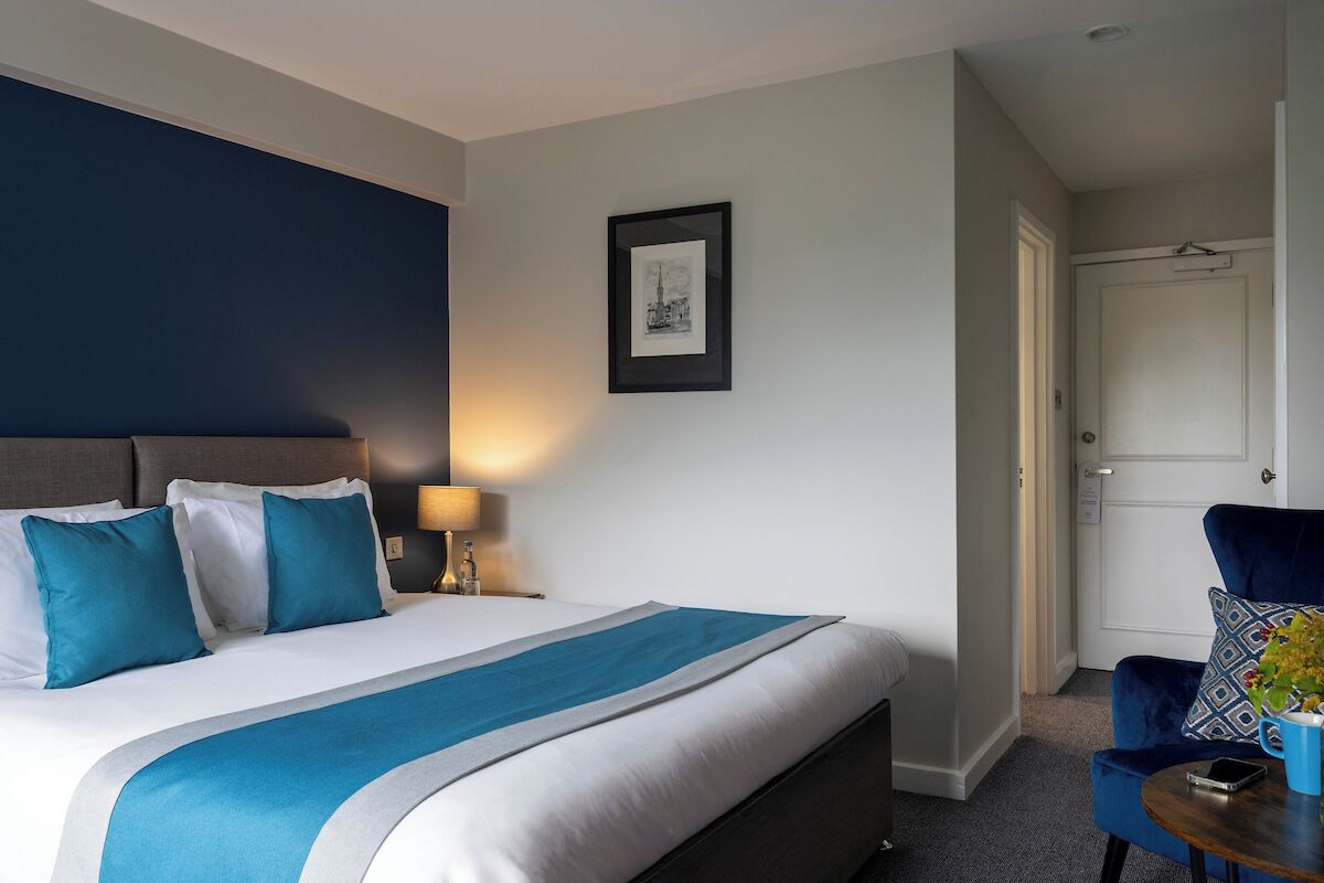 Una habitación de hotel con cama, una silla, una mesa y una puerta.