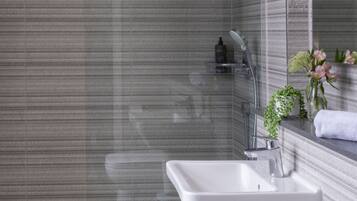Un baño moderno con ducha envuelta en vidrio, un lavabo blanco y un espejo.