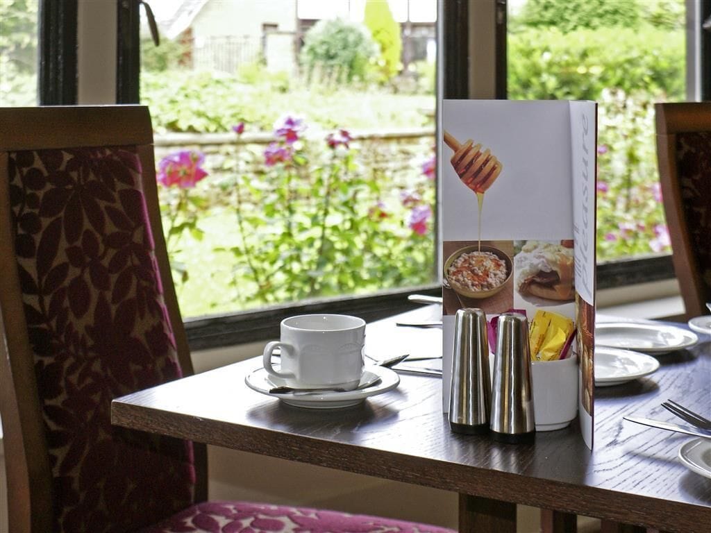 Une table avec une tasse et une soucoupe blanches, des salières et des poivrières, et un menu.