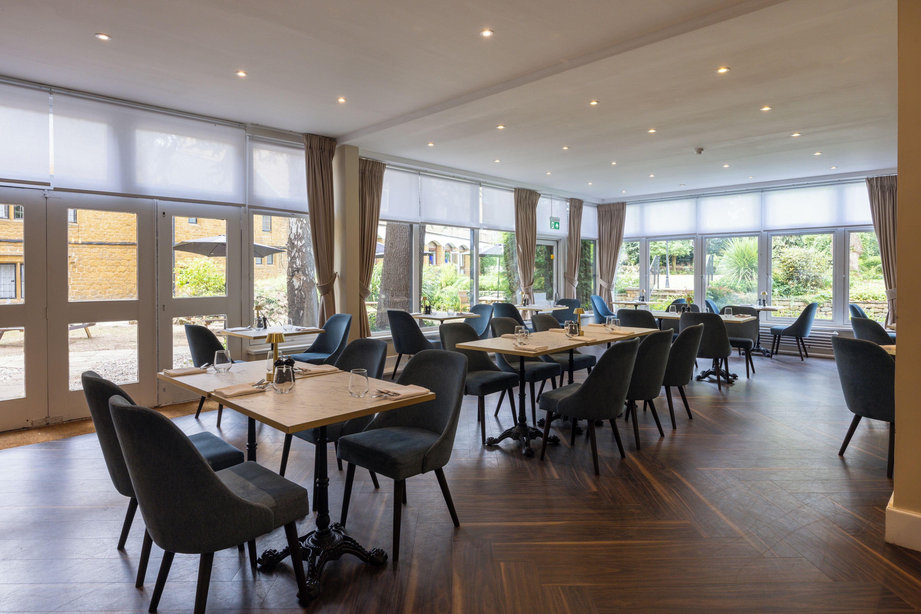 A conference room with tables and chairs, large windows, and a view of the outdoors.