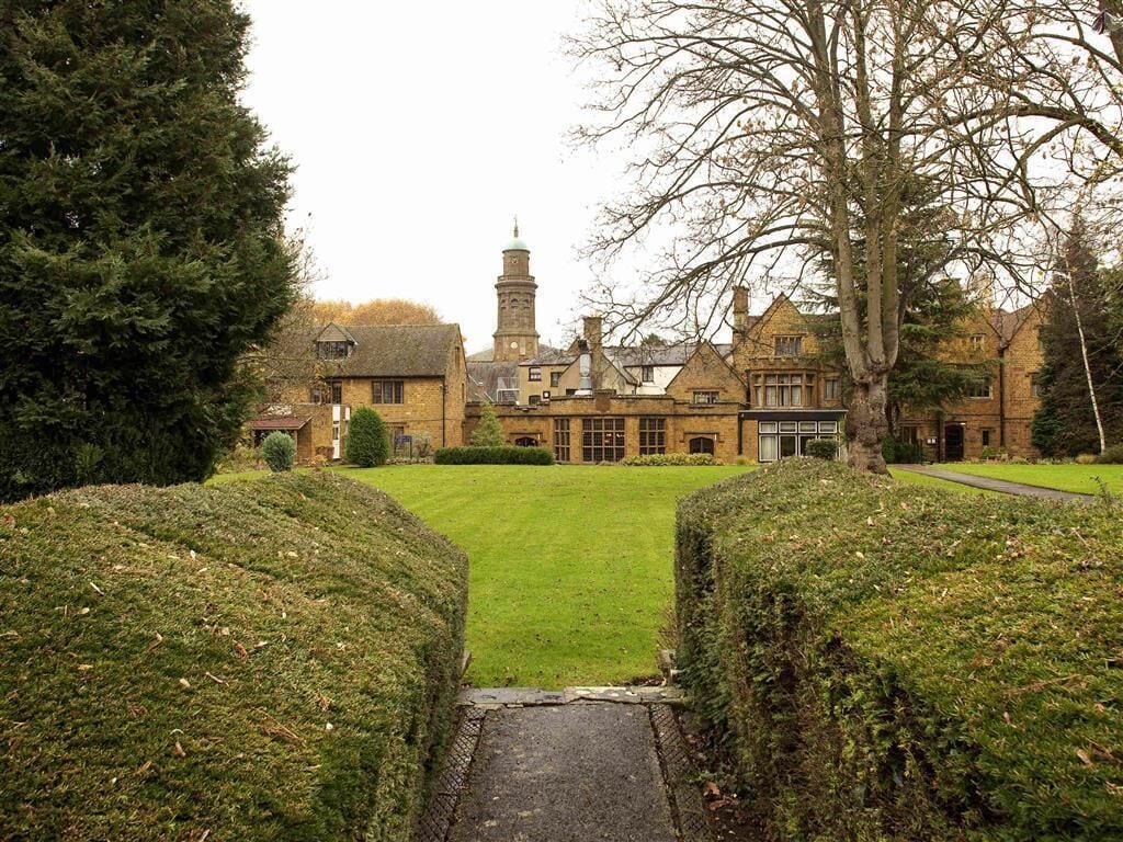 A traditional building with a central lawn and a pathway leading to the entrance.