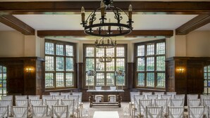 Une cérémonie de mariage avec des rangées de chaises, une allée centrale et un lustre.