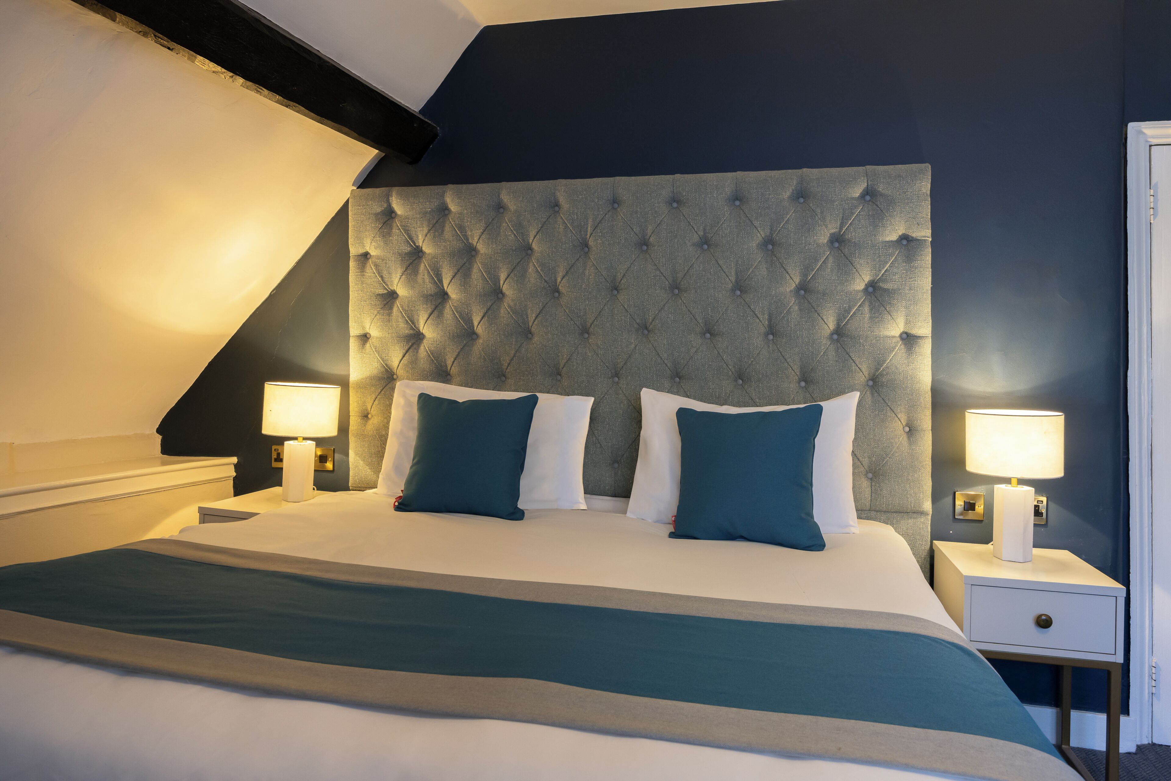 A bedroom with a large bed, two bedside lamps, and a tufted headboard.