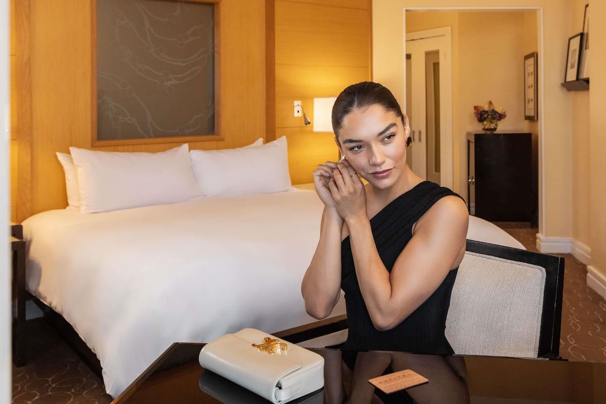 Una camera d'hotel con un letto, un comodino, una lampada e un quadro appeso al muro.