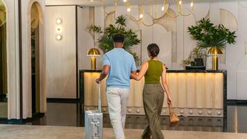 Uma receção com design moderno, um homem com mala e uma mulher a carregar uma bolsa.