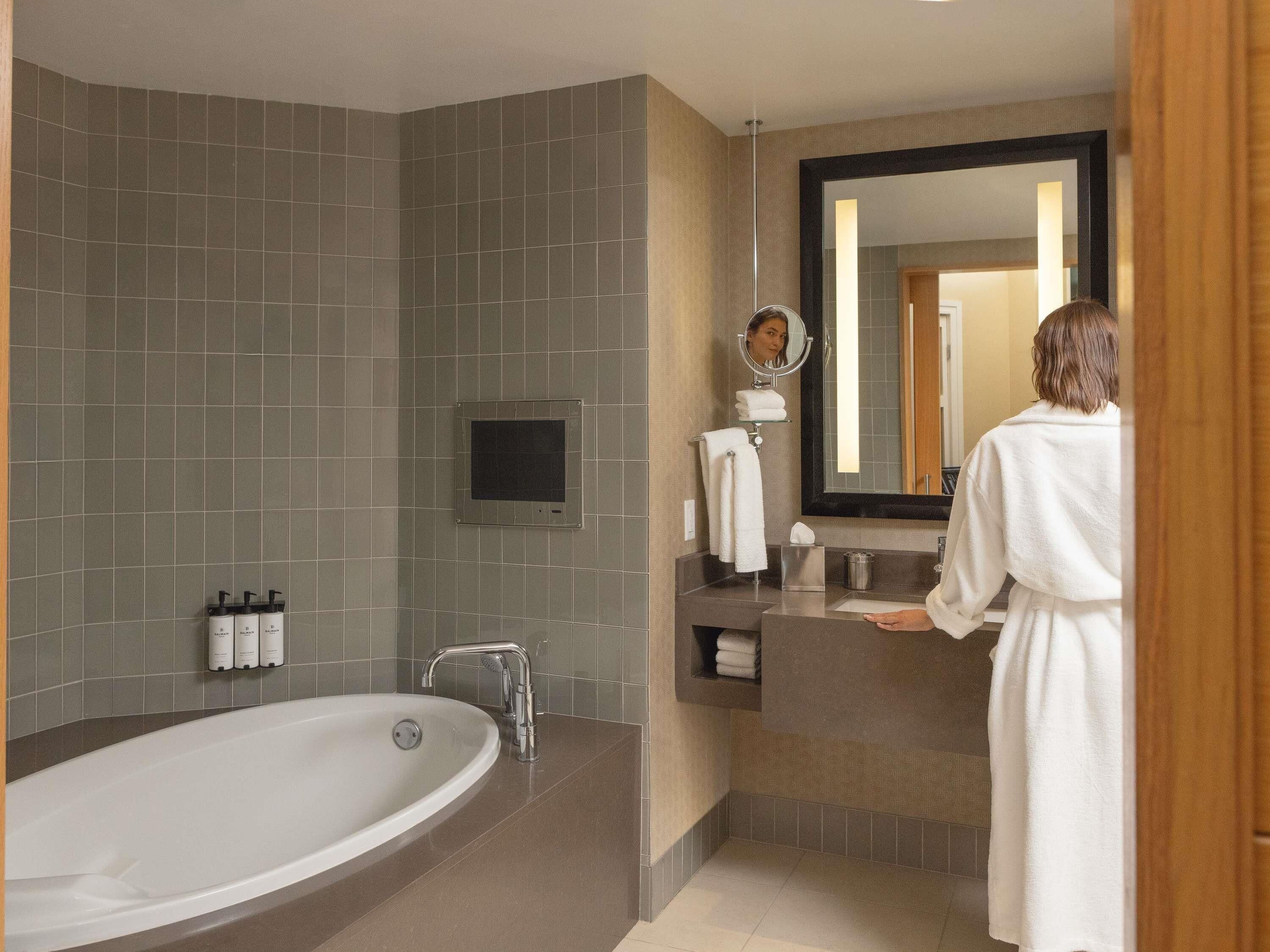 Un baño moderno con una bañera grande, un tocador con espejo y un perchero para toallas.