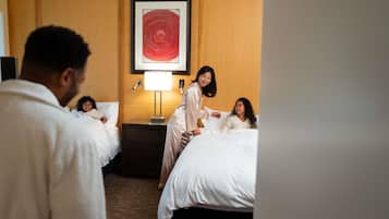 A hotel room with two beds, a nightstand with a lamp, and a framed artwork on the wall.