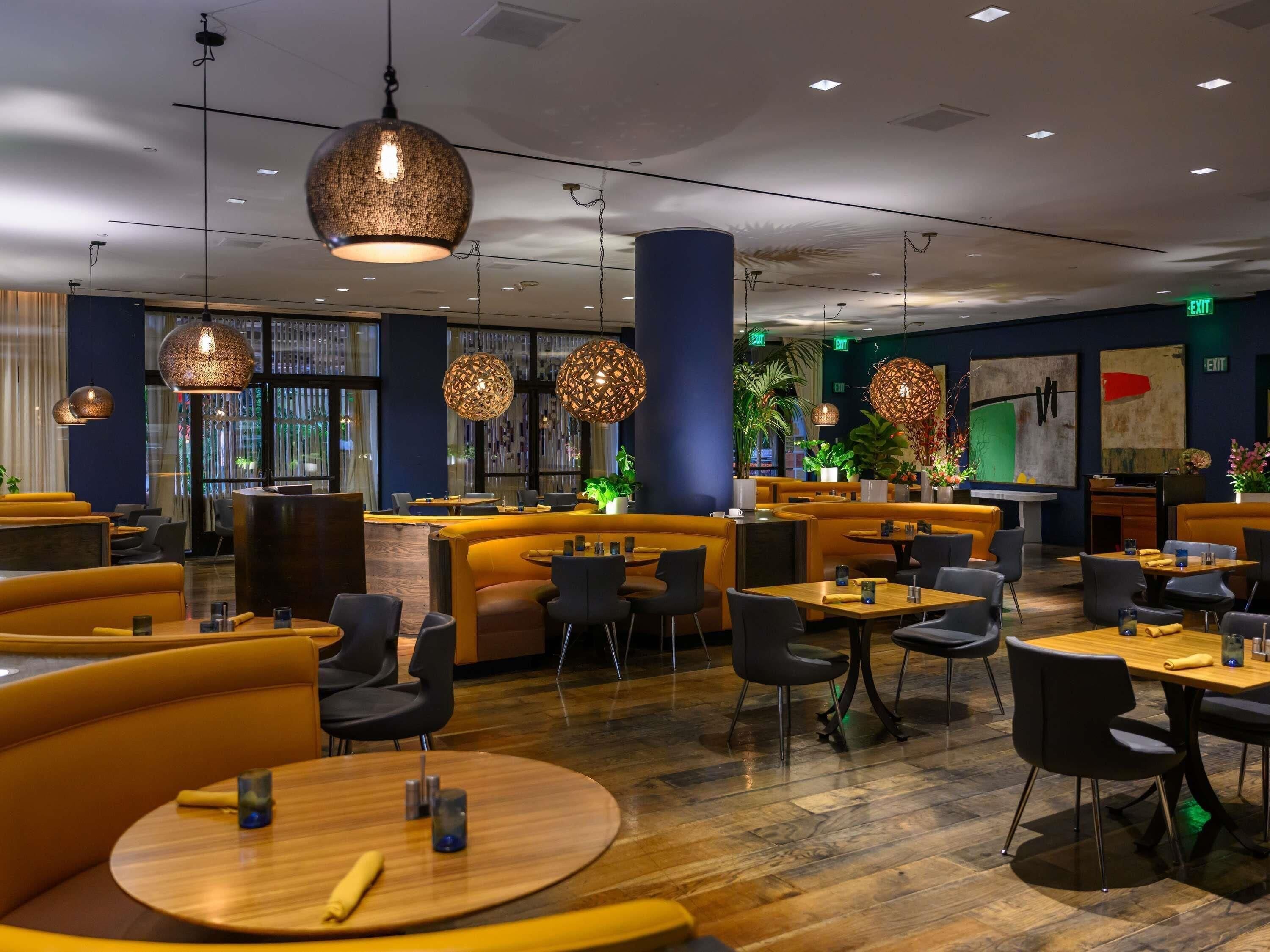 A modern restaurant interior with round tables, black chairs, and unique hanging light fixtures.