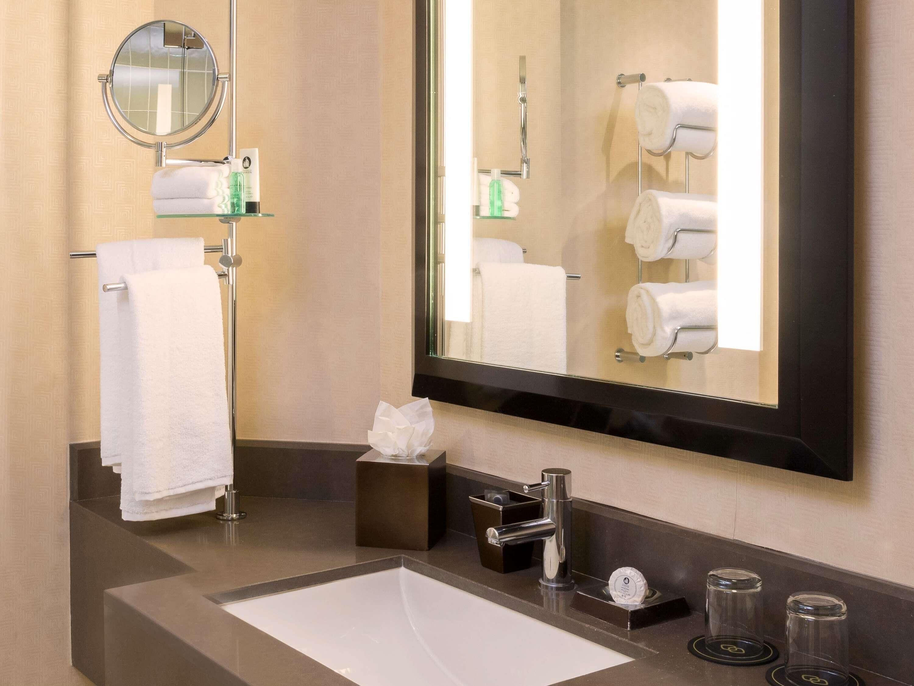 Une salle de bain moderne avec un grand miroir, un lavabo et un porte-serviettes.