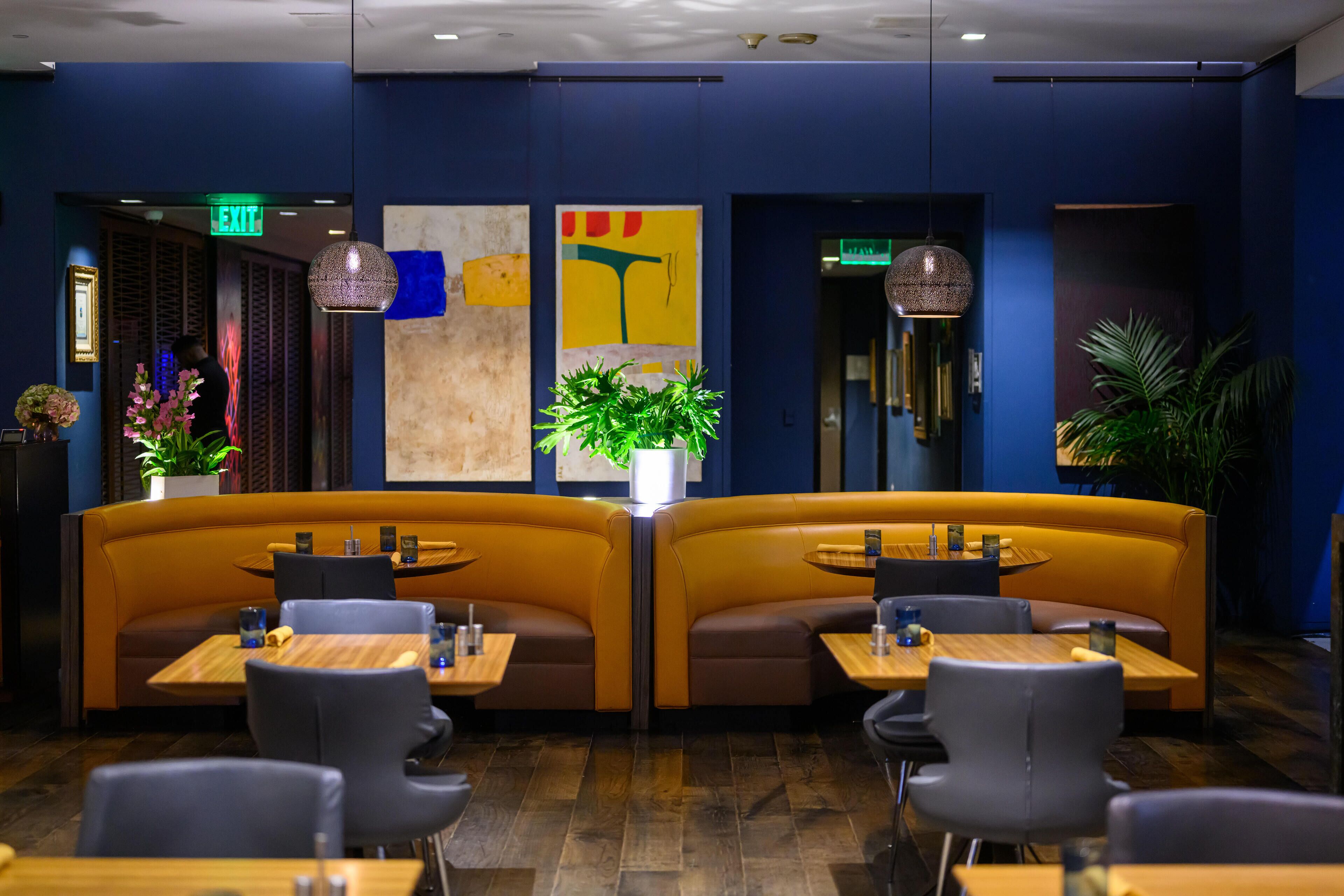 A restaurant with booth seating, tables, and hanging pendant lights.
