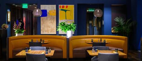 A restaurant with booth seating, tables, and hanging pendant lights.