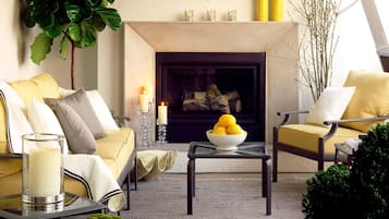 Una sala de estar acogedora con chimenea, un sofá, sillones, una mesita de centro y un frutero.