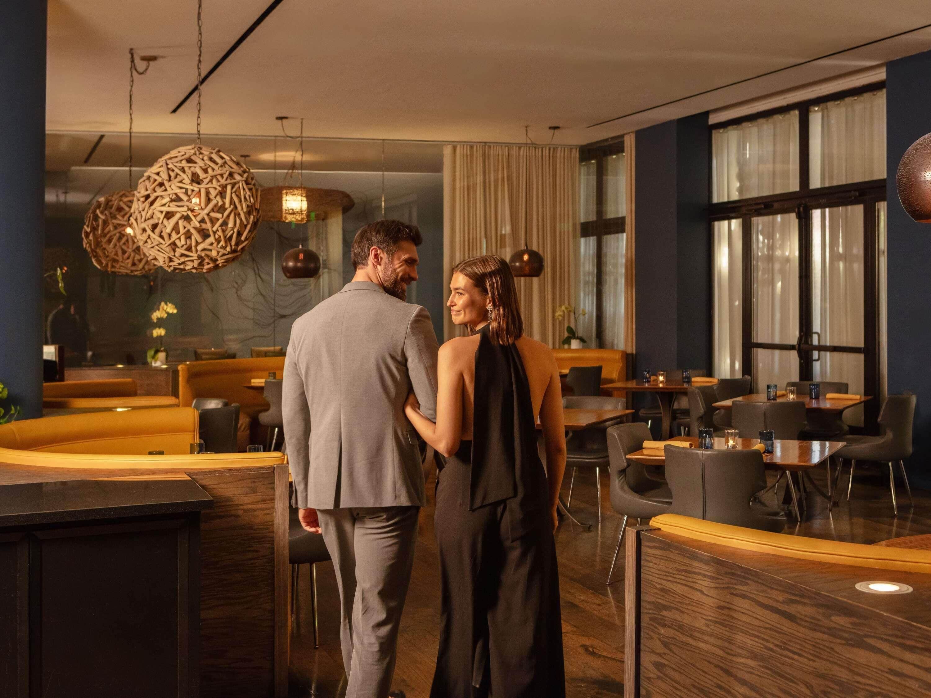 Un moderno vestíbulo de hotel con un mostrador de recepción curvo, zonas de estar y grandes ventanales.