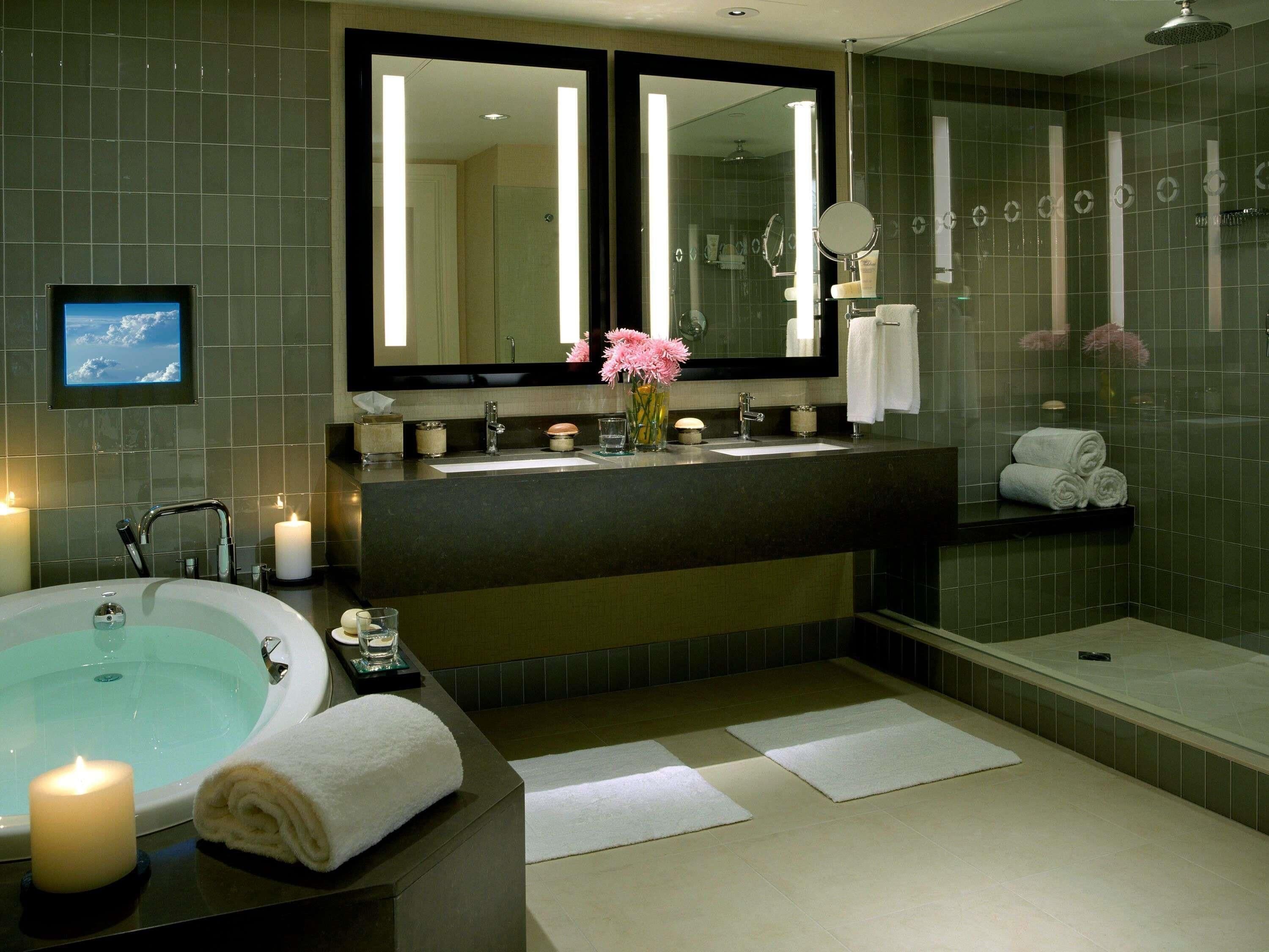 A modern bathroom with a bathtub, a large mirror, a vanity with a sink, and a shower area.