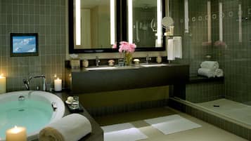A modern bathroom with a bathtub, a large mirror, a vanity with a sink, and a shower area.