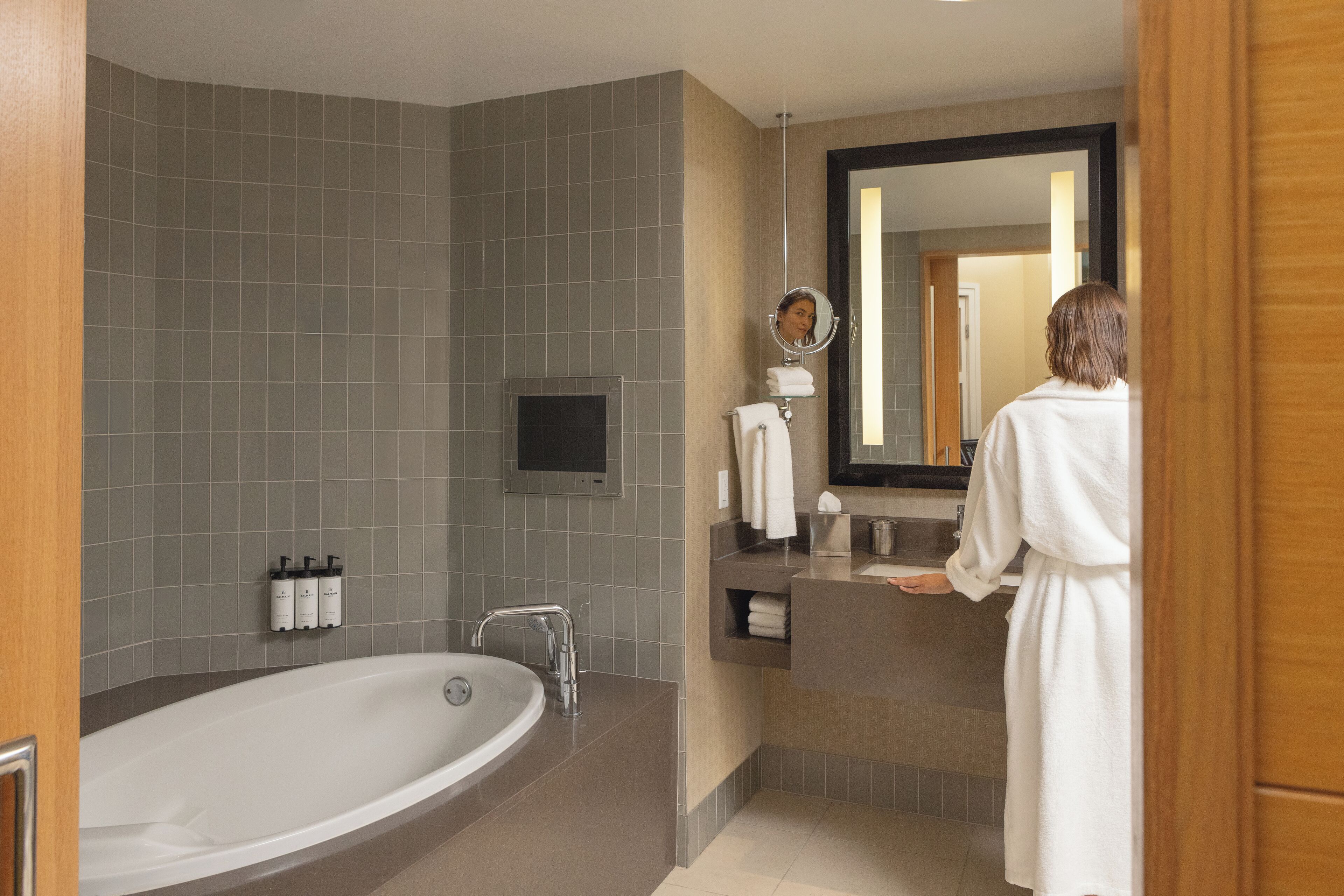 A modern bathroom with a large bathtub, a vanity with a mirror, and a towel rack.