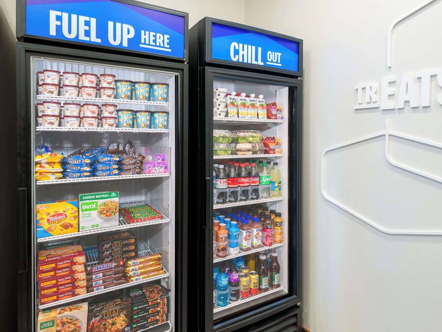 Zwei gekühlte Getränkespender, beschriftet mit „FUEL UP HERE“ und „CHILL OUT“, mit verschiedenen Getränken und Snacks.