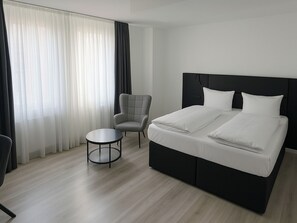 A modern hotel room with a large bed, a small round table, and a chair. - Dormero Hotel Dessau-Rosslau (Dessau-Rosslau)