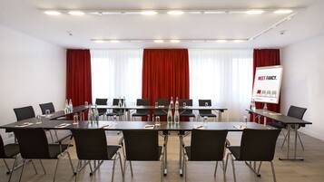 A conference room with a long table, black chairs, and a presentation screen.