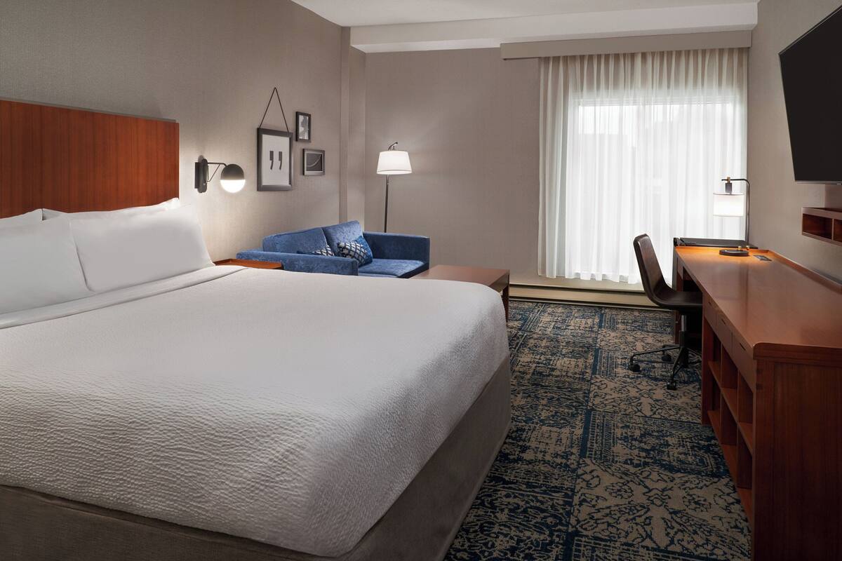 Une chambre d’hôtel avec un grand lit, un bureau, une chaise, un canapé et un téléviseur.