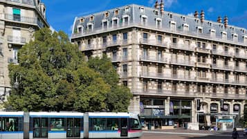 Eine Straßenbahn auf einem Stadtplatz, im Hintergrund ein großes historisches Gebäude.