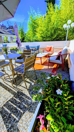 An outdoor patio with a table and chairs, surrounded by greenery and a white wall. - Ibis Grenoble Centre Bastille (Grenoble)