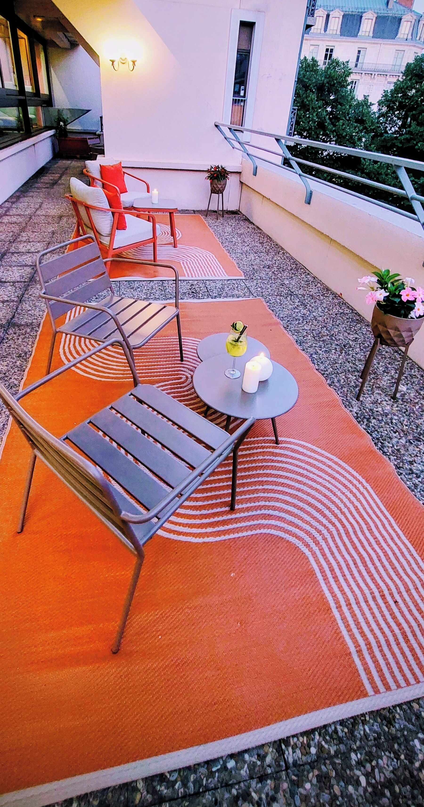 Une terrasse sur le toit avec des sièges en plein air, une table décorée de bougies et une plante en pot.