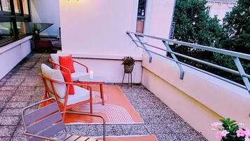 Une terrasse sur le toit avec des sièges en plein air, une table décorée de bougies et une plante en pot.