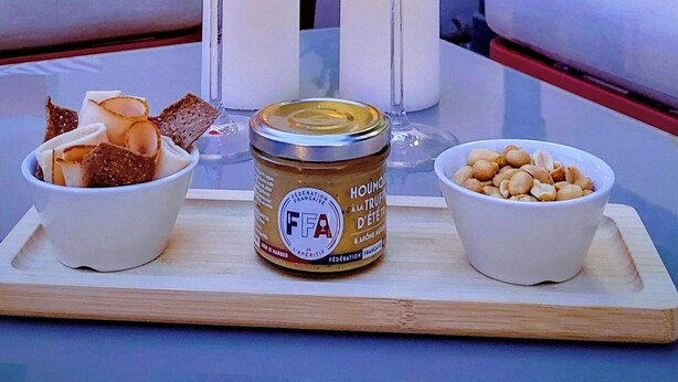 Una mesa con dos bebidas, un tarro de miel y un cuenco de nueces.