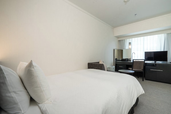 A hotel room with a large bed, a desk, a chair, a television, and a window with curtains. - Hotel Nikko Osaka (Osaka)