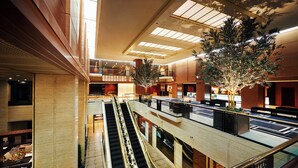 Un atrio de varios niveles con escaleras mecánicas, un árbol central y un diseño interior moderno.