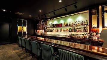 A bar area with a long counter, multiple shelves of bottles, and striped bar stools.