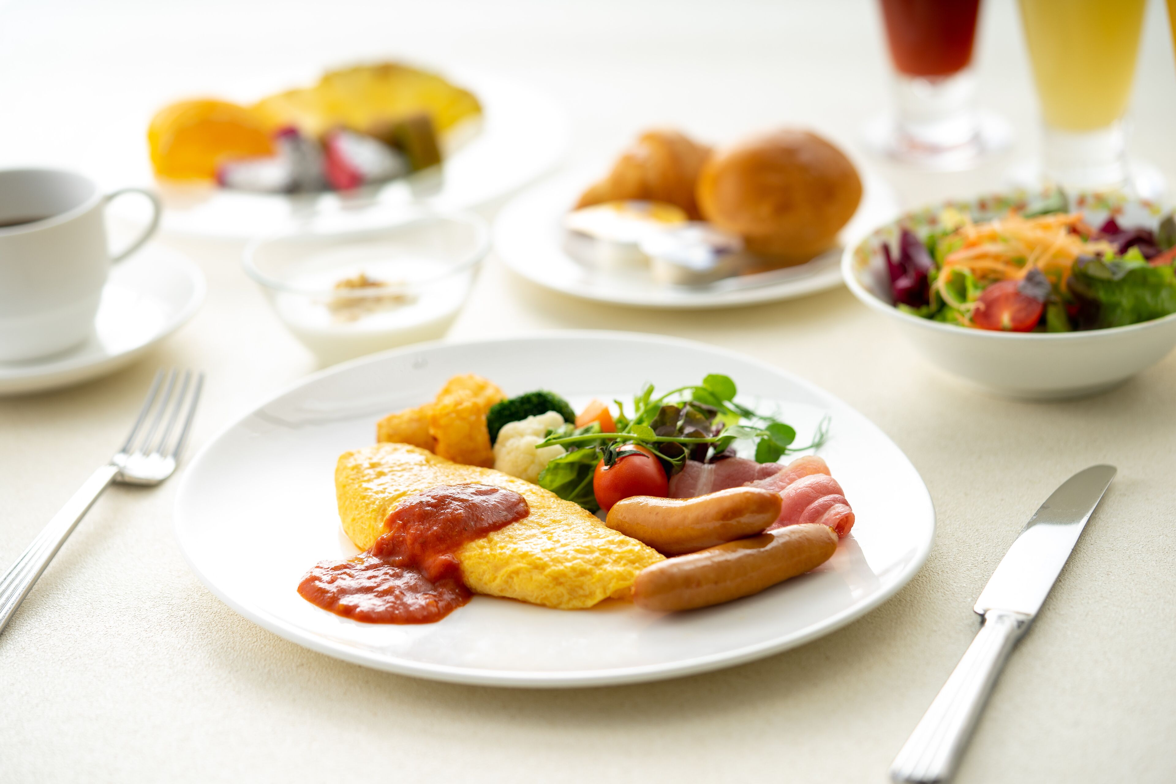Una mesa con un plato de huevos, salchichas y verduras, una taza de café y un vaso de jugo de naranja.