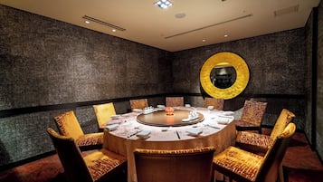 A conference room with a round table, chairs, and a large mirror on the wall.