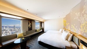 Una habitación de hotel con una cama grande, un sofá, un escritorio y vistas a la ciudad.