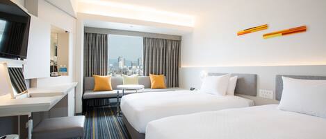 A hotel room with two beds, a desk, a TV, and a city view.