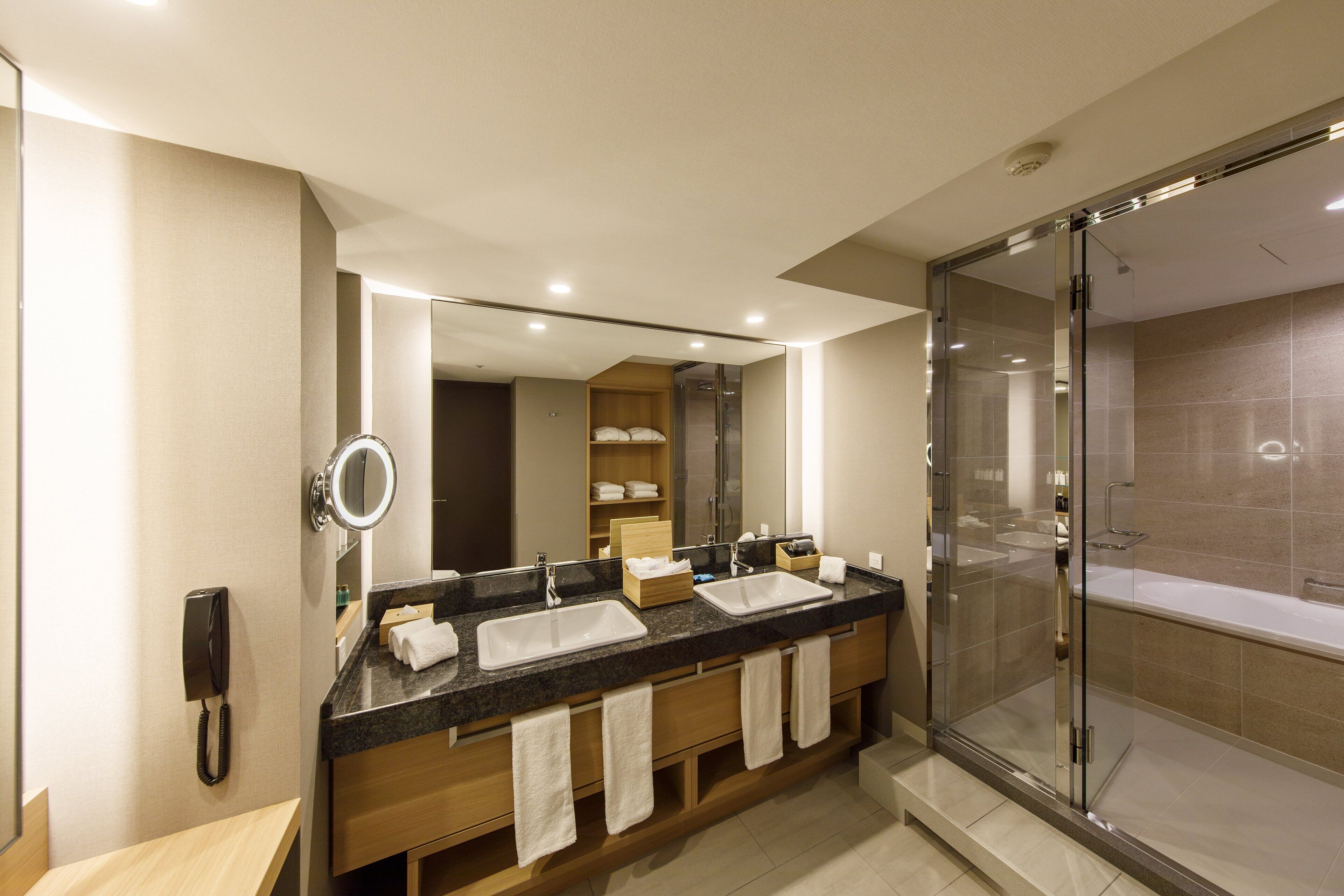 Un baño moderno con tocador doble, ducha con cerramiento de vidrio y espejo sobre el lavabo.