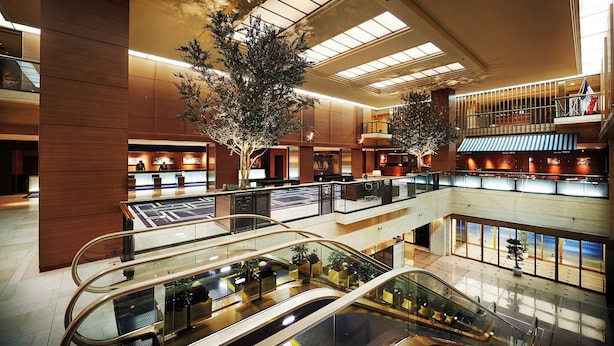 Un atrio de varios niveles con barandillas de cristal, escaleras mecánicas y plantas de interior.